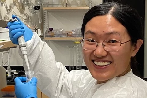 A lab researcher is holding a syringe in a vial.